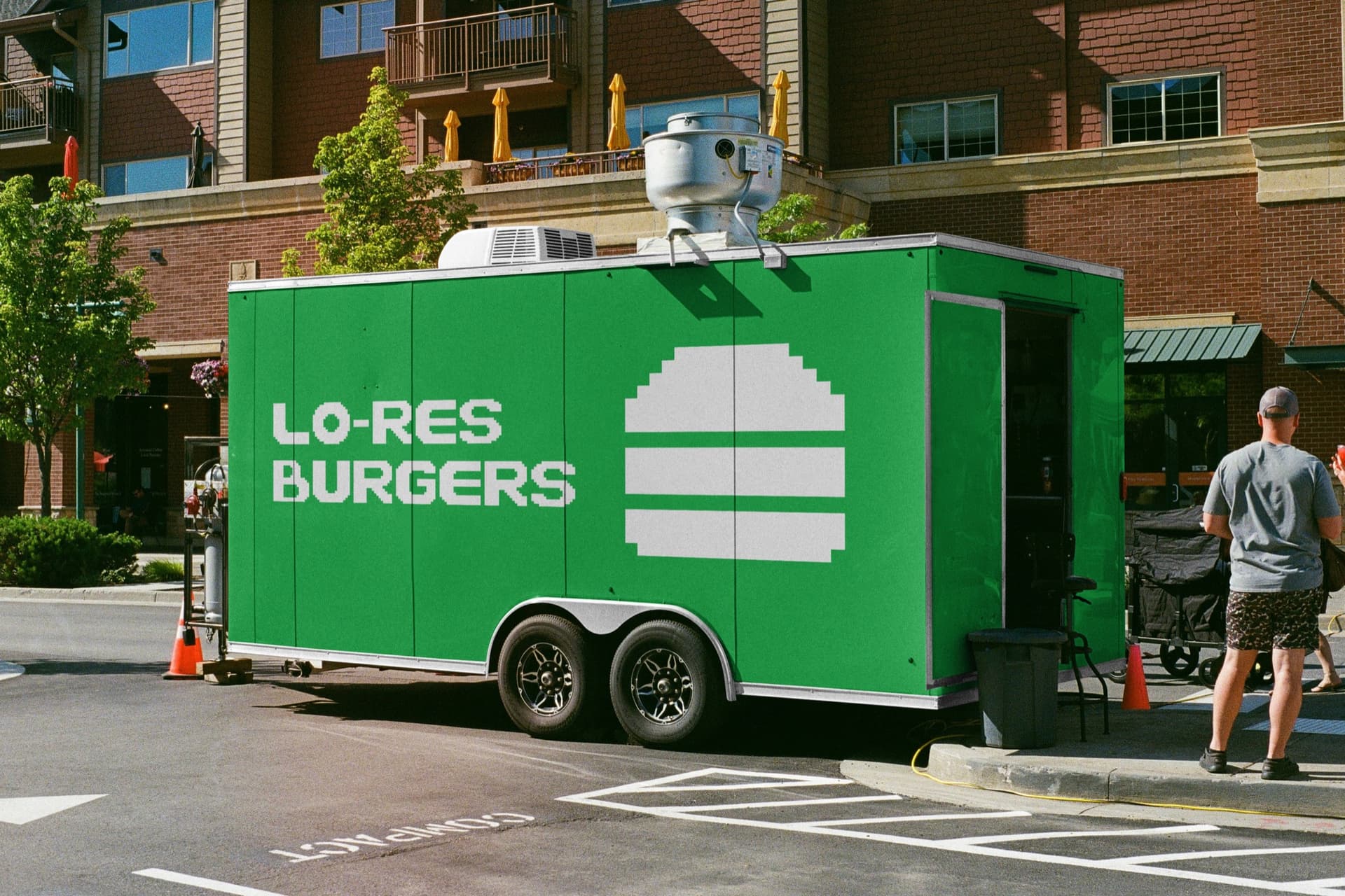 food trailer mockup wrapped in green with the Lo-Res Burgers wordmark and a pixel burger icon, parked on a city street