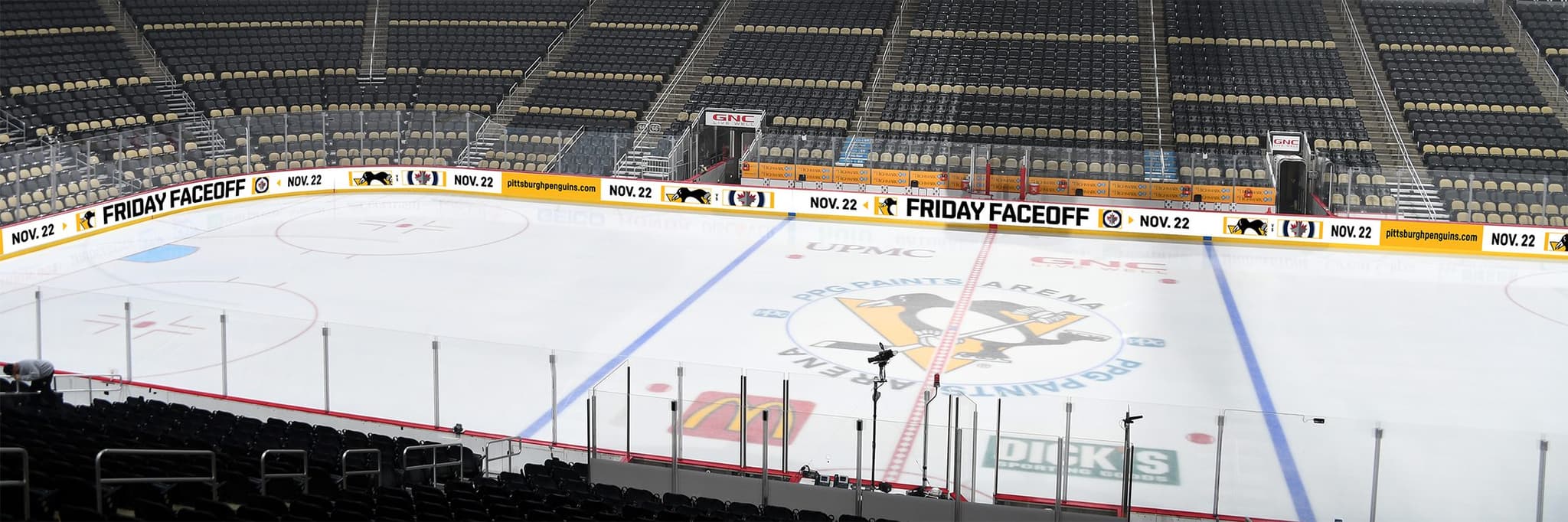 PPG Paints Arena before a game, a lit gold ribbon board running along the dasher boards around the rink with FRIDAY FACEOFF repeating along its length